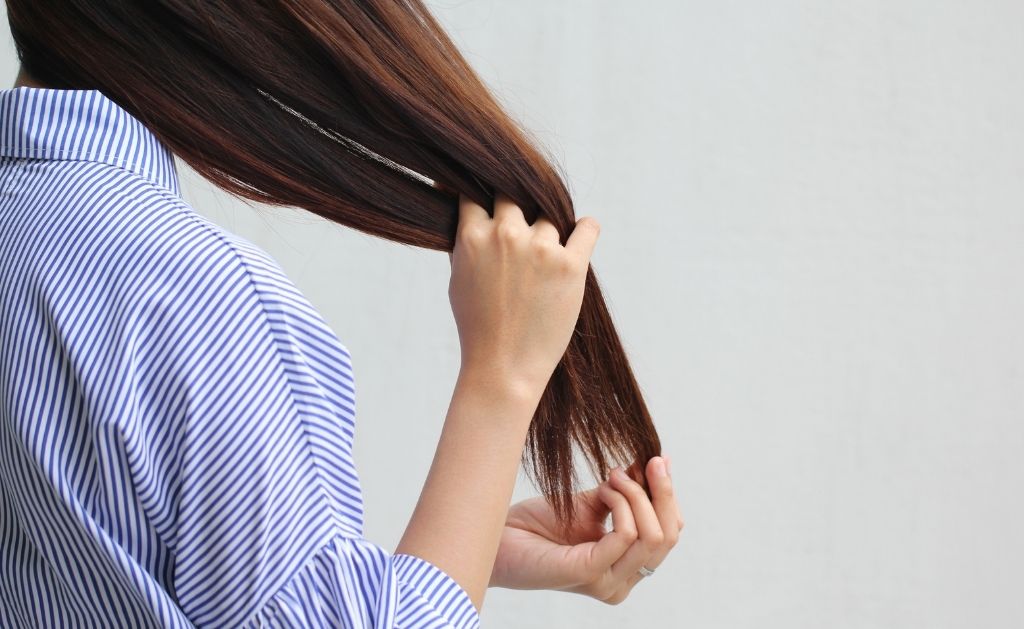 ragazza di spalle con mani fra i capelli